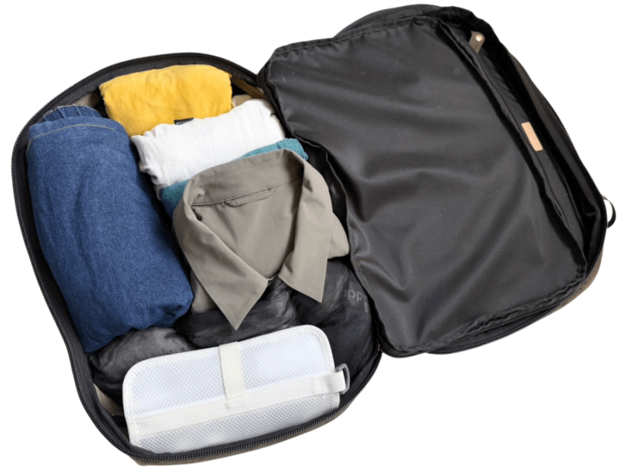 Open black suitcase filled with folded clothes: blue jeans, yellow and white shirts, gray shirt, teal item, and a white packing cube.