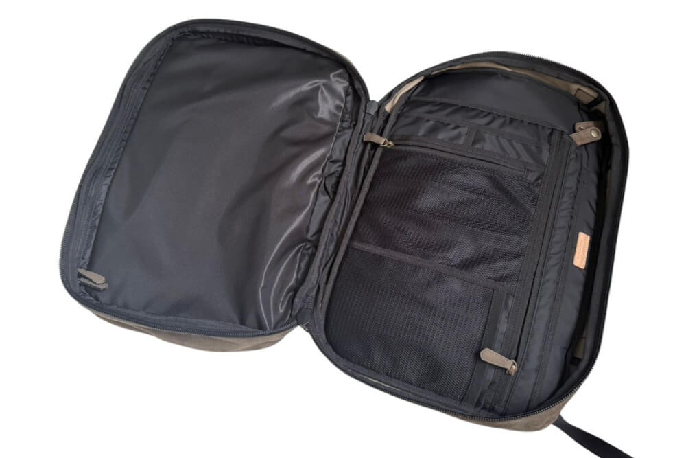Open compact travel case showing internal compartments: mesh pocket, elastic straps, and zipper closures.