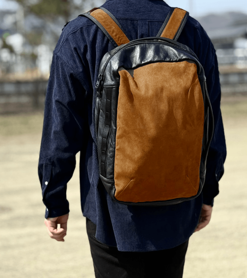 Person seen from behind wearing a brown-and-black backpack outdoors.