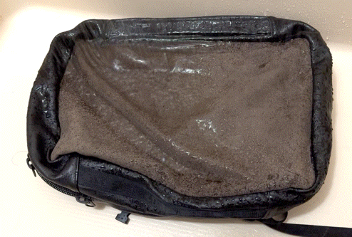 Black zippered pouch with a scorched brown interior exposed, showing heat-damaged edges.
